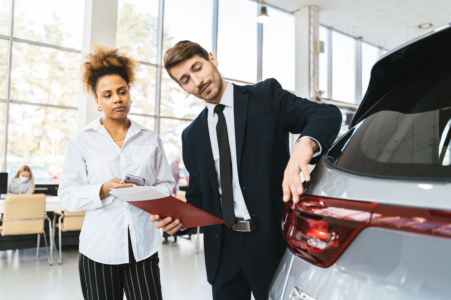 Cliente étudiant une offre automobile avec un conseiller en concession